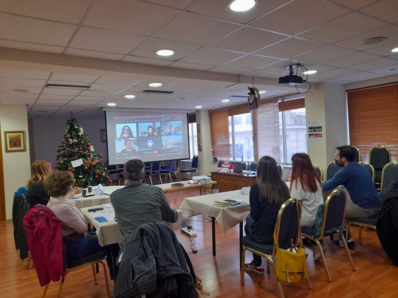 Members gathered and seated in a room where they attend a video conference.